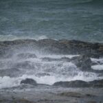 Wellen brechen bei Sturm an einer felsigen Küste