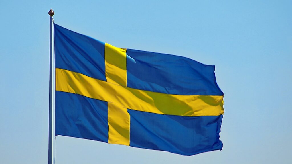 Die blau-gelbe Flagge Schwedens weht vor dem Himmel