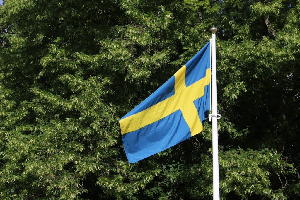 "Alter Schwede!" – hvor det tyske udtryk kommer fra 1 Schwedische Flagge weht neben Bäumen im Stadtpark von Örebro