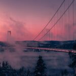 Hängebrücke Högakustenbron über einem nebligen Fluss im rosa Morgenlicht