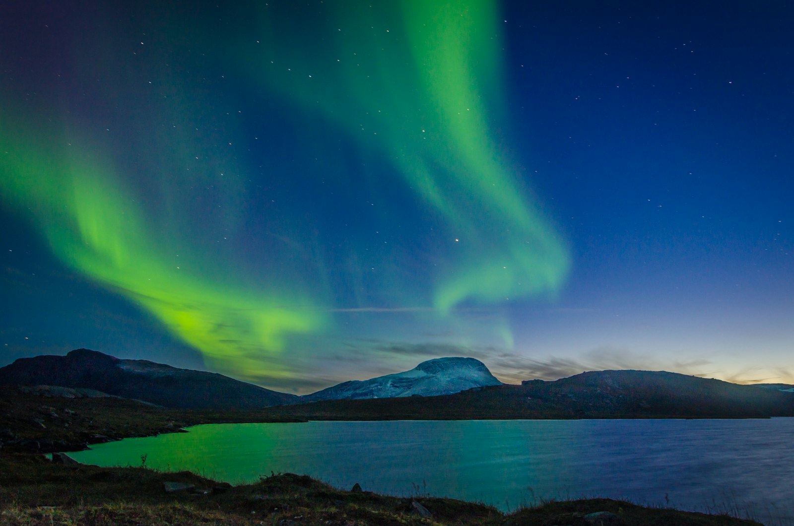 Nordlys over en bjergsø i Abisko Nationalpark