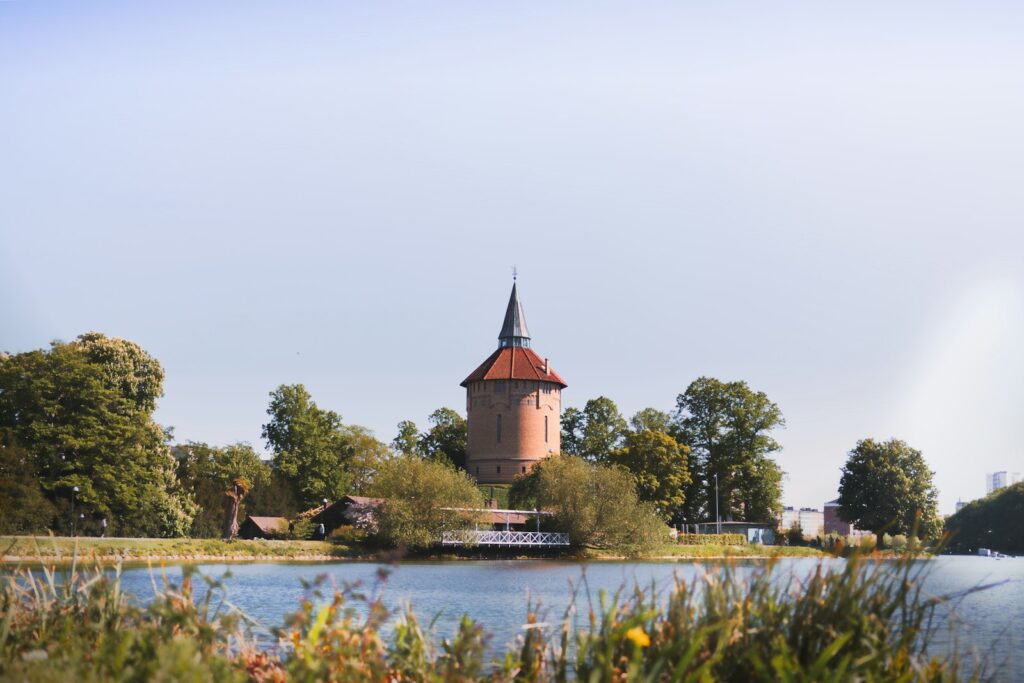 Turm eines Gebäudes neben einem See und Park in Malmö