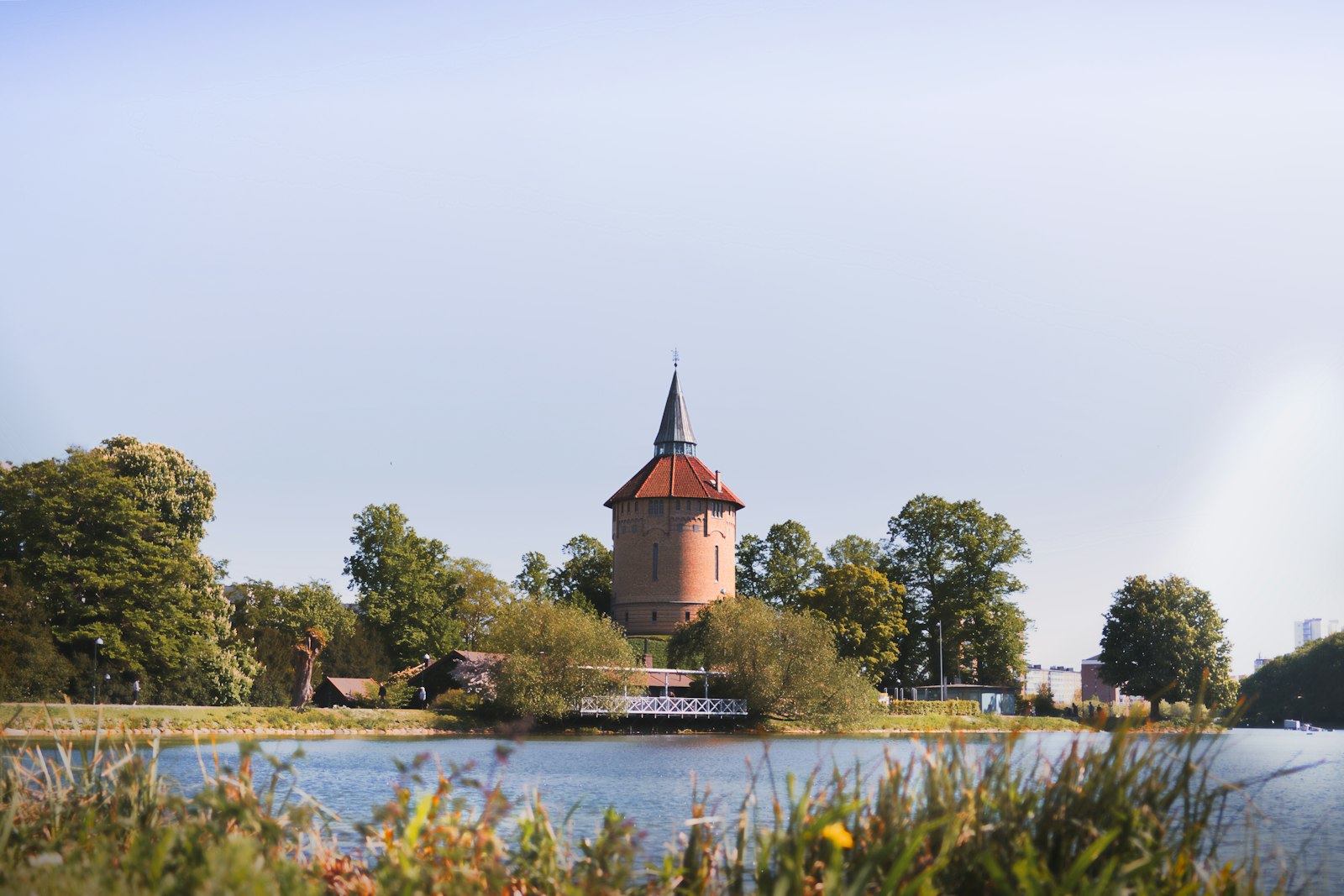 Tower of a building next to a lake and park in Malmö