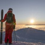 Skifahrer mit Skiern bei Sonnenaufgang über einer Wolkendecke in Åre