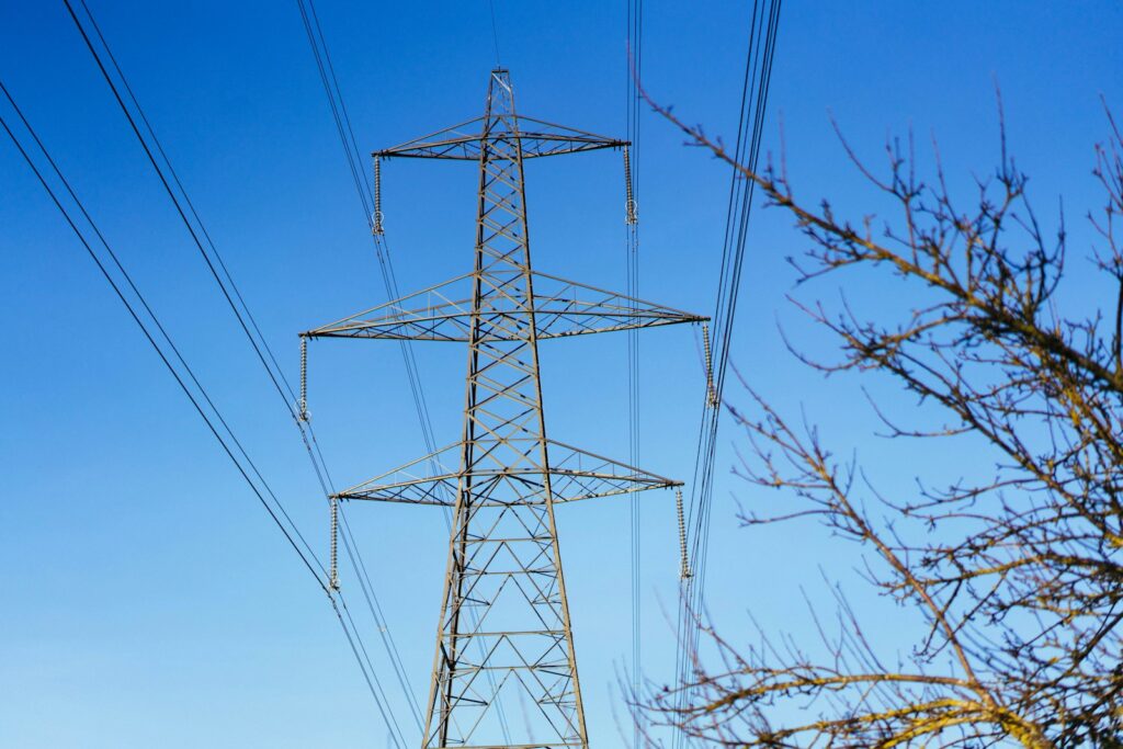 Hochspannungsmast mit Stromleitungen vor blauem Himmel