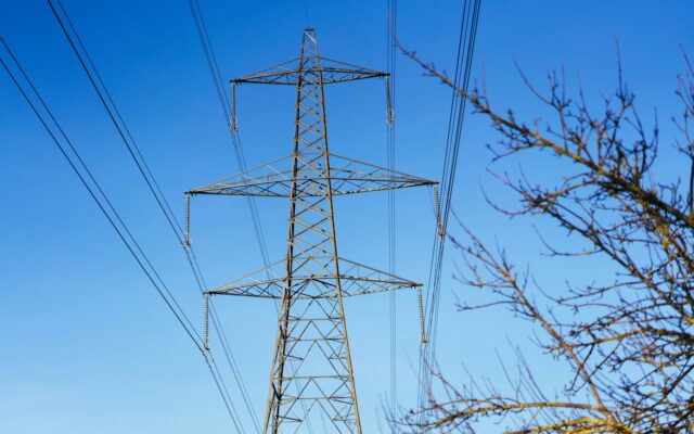 Hochspannungsmast mit Stromleitungen vor blauem Himmel