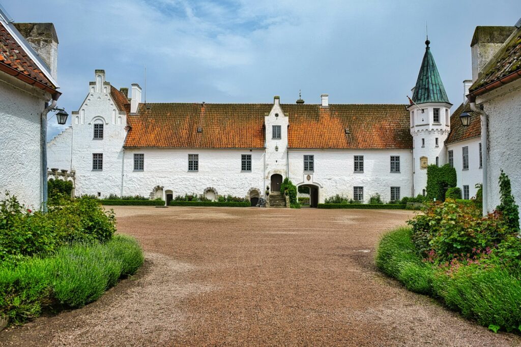 Weißes Schloss mit rotem Dach und grünem Turm, Bosjökloster in Skåne