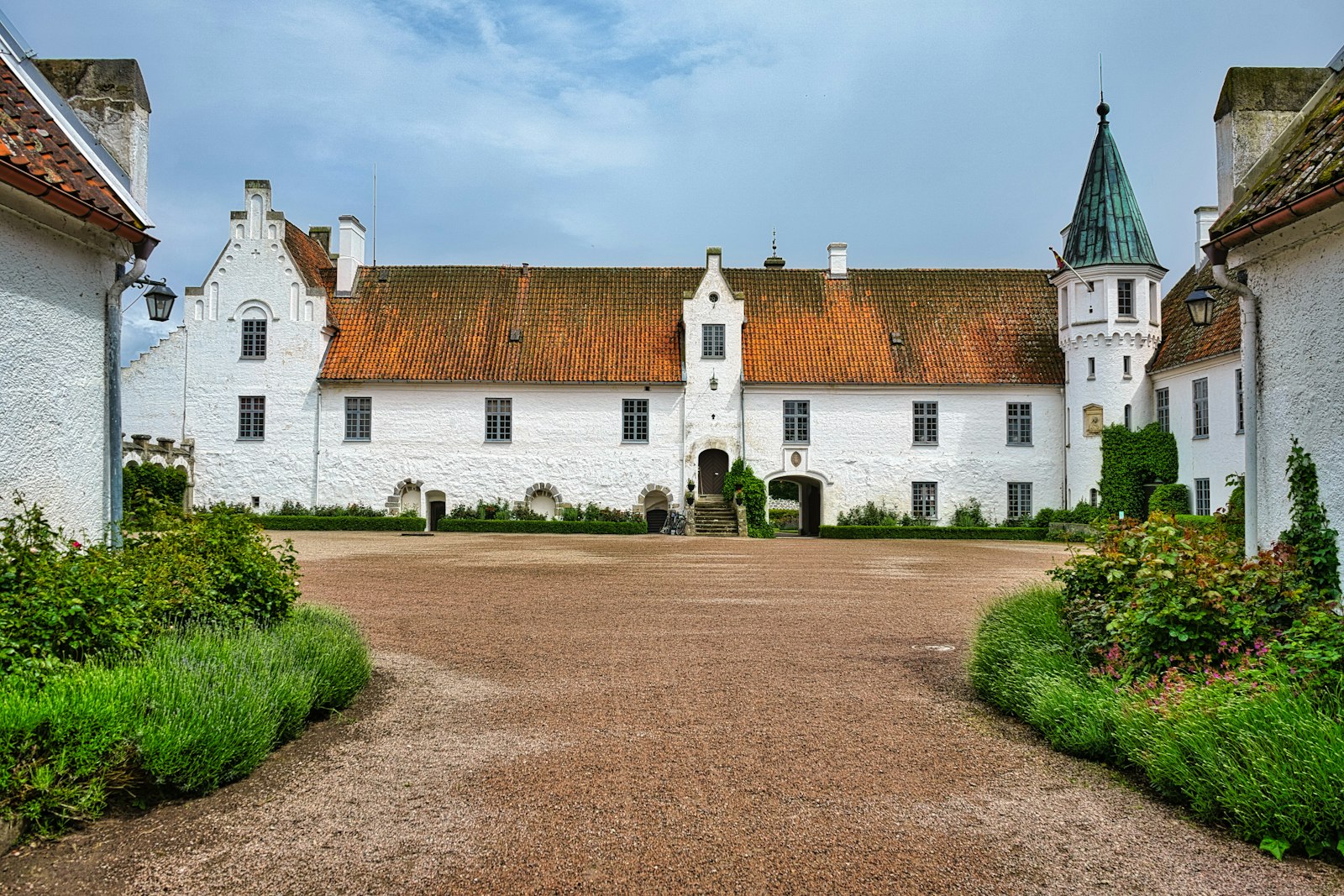 White castle with a red roof and green turret, Bosjökloster in Skåne